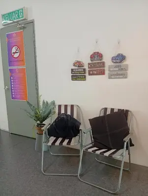 two chairs sitting next to a wall with signs at Bajet Homestay - Teratak Singgah in Seri Iskandar