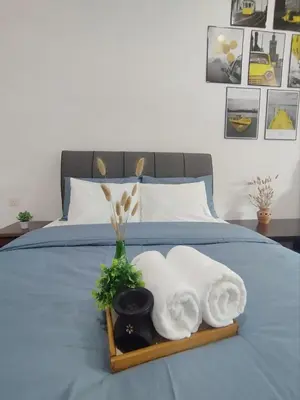 a tray with towels and a vase on a bed at Ipoh Home Story Newly Renovated Bercham Landed Double Storey For 10pax in Ipoh