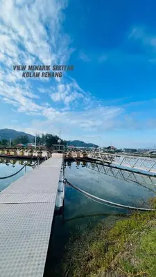 a boat sitting on the water next to a dock at Marina Island Lumut in Lumut