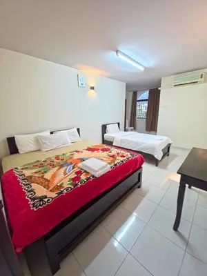 a bedroom with two beds and a desk in it at Zahaar KN Inn in Batu Ferringhi