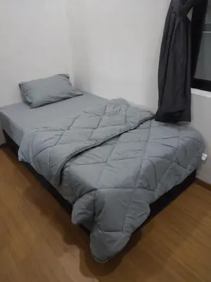 a bed with a gray comforter in a room at Oasis Condominiums Ipoh in Ipoh