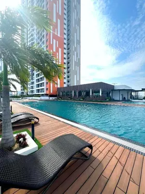 a swimming pool with chairs and a palm tree and buildings at Meritus Residence 4min to Penang Bridge in Perai