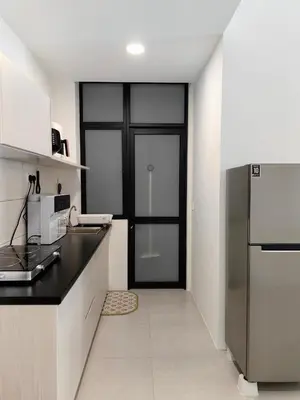 a kitchen with a black counter and a refrigerator at The Glen Apartment Kuching in Gua Sai