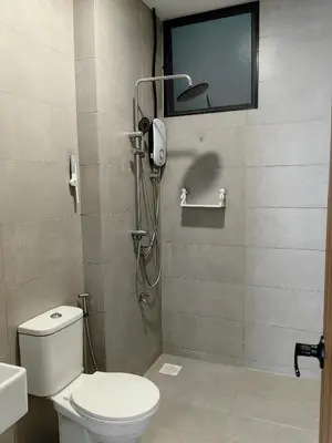 a bathroom with a shower with a toilet and a television at The Glen Apartment Kuching in Gua Sai