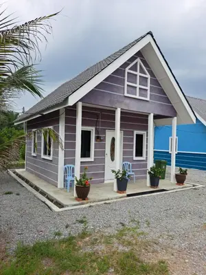a small purple house with two chairs and a porch at Teratak Sumayyah 1 - For Islam Only - Pondok Lenggong in Kampong Banggol Belimbing