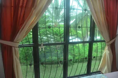 a window with a view of a forest at Kulim LakeView Homestay at Golf Resort in Kulim