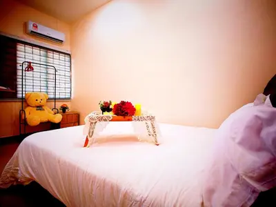 a bed with a table with flowers and a teddy bear at Ipoh Happy Home Boutique Villa by City Home Empire in Ipoh