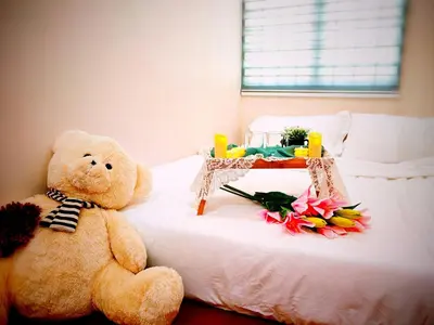 a teddy bear sitting on a bed with flowers on it at Ipoh Happy Home Boutique Villa by City Home Empire in Ipoh