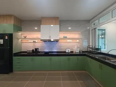a kitchen with green cabinets and a black counter top at Hejau Golf Villa in Tanah Rata