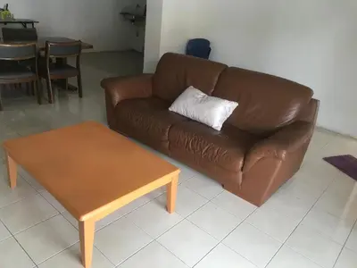 a brown leather couch and a coffee table in a living room at Batu Kawan HS in Simpang Ampat