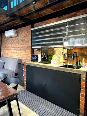 a kitchen with a counter with a sink and a table at Kurie Redbrick House in Balik Pulau