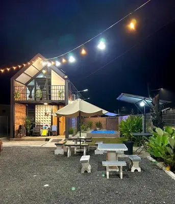 a group of picnic tables and umbrellas at night at Kurie Redbrick House in Balik Pulau