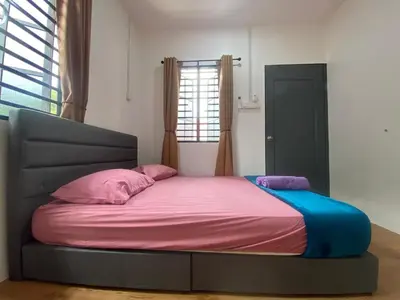 a bed in a room with a large bed with pink and blue sheets at Roomstay Cikgu Mie in Bayan Lepas