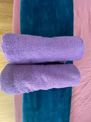 two purple towels on top of a bed at Roomstay Cikgu Mie in Bayan Lepas