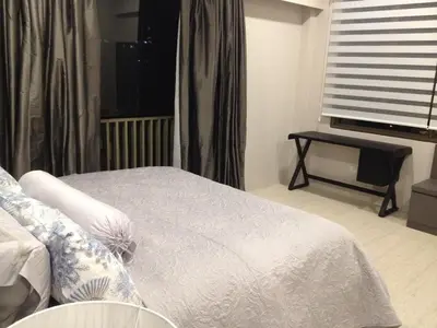 a bedroom with a bed with a window and a table at By the Sea PENTHOUSE duplex in Batu Ferringhi