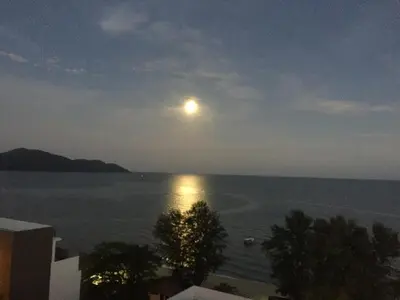 a view of the moon over the water at night at By the Sea PENTHOUSE duplex in Batu Ferringhi