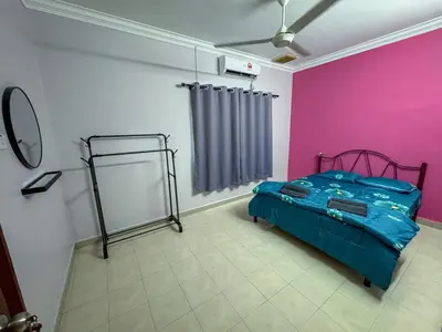 a bedroom with a bed and a pink wall at M S Villa Homestay Ayer Tawar in Ayer Tawar