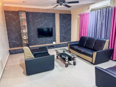a living room with black leather furniture and a tv at M S Villa Homestay Ayer Tawar in Ayer Tawar