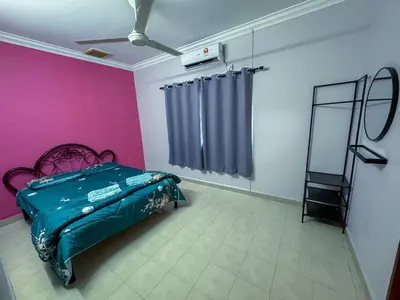 a bedroom with a bed and a pink wall at M S Villa Homestay Ayer Tawar in Ayer Tawar