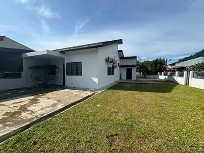a white house with a grass yard in front of it at Rumah Bonda in Gua Sai