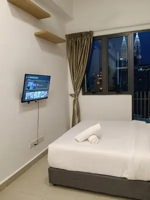 a bedroom with a bed and a flat screen tv at Infinitum suites at colony KLCC in Gua Sai