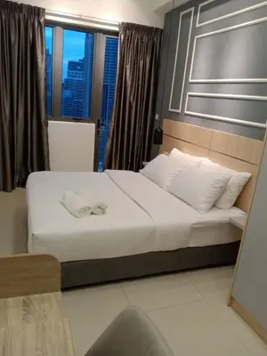 a bedroom with a bed with white sheets and a window at Infinitum suites at colony KLCC in Gua Sai