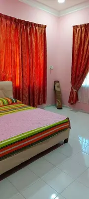a bedroom with a bed and red curtains at ASTANA INN HOMESTAY Balik Pulau in Balik Pulau