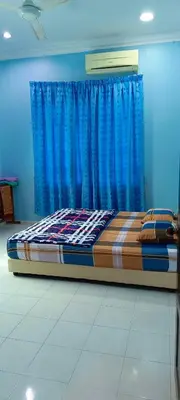 a bed sitting in a room with blue curtains at ASTANA INN HOMESTAY Balik Pulau in Balik Pulau