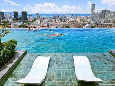 a man in a swimming pool with a city in the background at Beacon Executive Suite Penang George Town in George Town