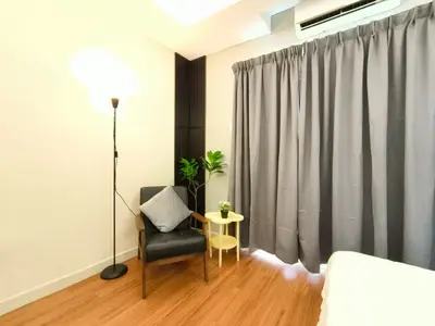 a bedroom with a bed and a chair and a table at JJ's Modern Suite Kampar- Near UTAR in Kampar