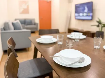 a wooden table with white plates and bowls on it at Resandau Stay Ipoh - Nearby Ipoh Town - Private Car Park and Lift - Whole unit & Coliving in Ipoh