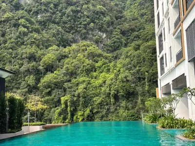 a pool of blue water in front of a mountain at Theme Park Ipoh - Onsen Premier Suites By LUX SUITE in Ipoh