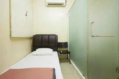 a small room with a bed and a chair at Ros Heritage Motel in George Town
