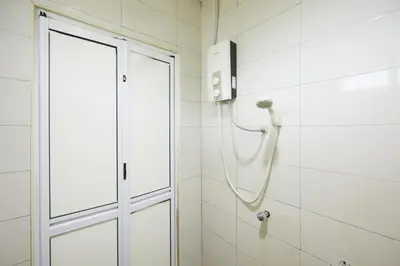 a shower with a hose in a white tiled bathroom at Ros Heritage Motel in George Town