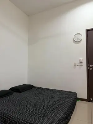a bed in a room with a white wall at home sweet home in Kampong Batu Maung