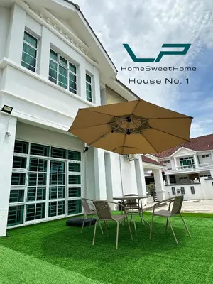 a table and chairs with an umbrella in front of a house at Penang Balik Pulau BBQ & KARAOKE Home in Balik Pulau