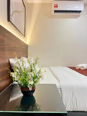 a vase of flowers sitting on a table next to a bed at Hotel Istanaku , Ipoh, Perak in Ipoh