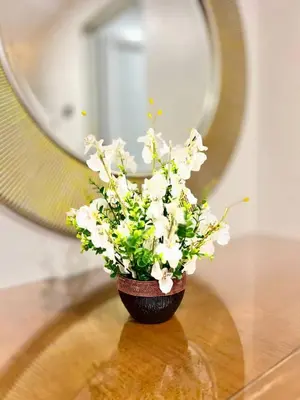a vase of flowers on a table in front of a mirror at Hotel Istanaku , Ipoh, Perak in Ipoh
