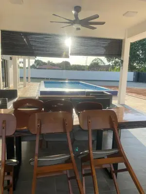 a dining room with a table and chairs and a swimming pool at Untung5tay in Gua Sai