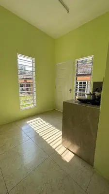 an empty room with green walls and two windows at Baitul Ilmi Homestay in Kuala Kangsar