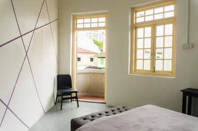 a room with a bed and a window and a chair at KITA Hostel in George Town