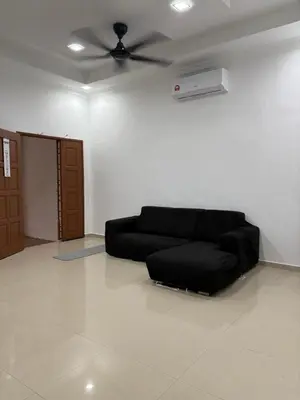 a living room with a black couch and a ceiling fan at Bidor Homestay in Bidur