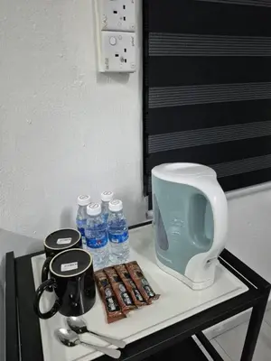 a table with a coffee maker and bottles of water at Syaf Homestay in Lunas