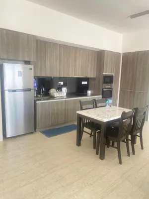 a kitchen with a table with chairs and a refrigerator at By The Sea in Batu Ferringhi