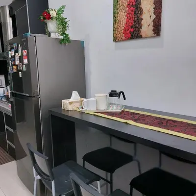 a kitchen with a counter with chairs and a refrigerator at Alisa Homestay in Lunas