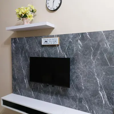 a flat screen tv on a wall with a clock at Alisa Homestay in Lunas