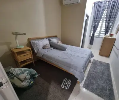 a bedroom with a bed and a lamp on the floor at Alisa Homestay in Lunas