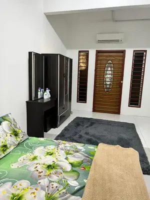 a living room with a bed and a table and some doors at Dlaili Homestay in Tanjung Karang