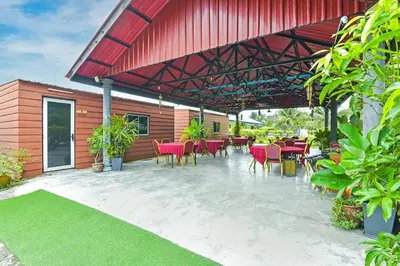 a patio with tables and chairs and a red roof at Hotel O Asiacamp Chalet Tanjung Karang in Kuala Selangor