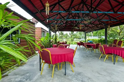 a patio with red tables and chairs and plants at Hotel O Asiacamp Chalet Tanjung Karang in Kuala Selangor